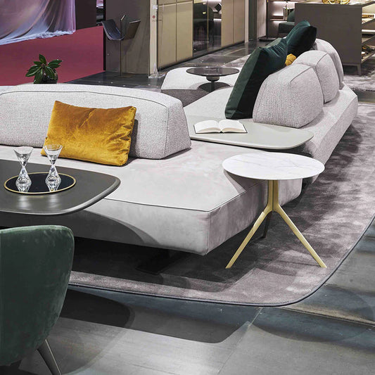 Side table next to sofa with gold flared base and marble top.