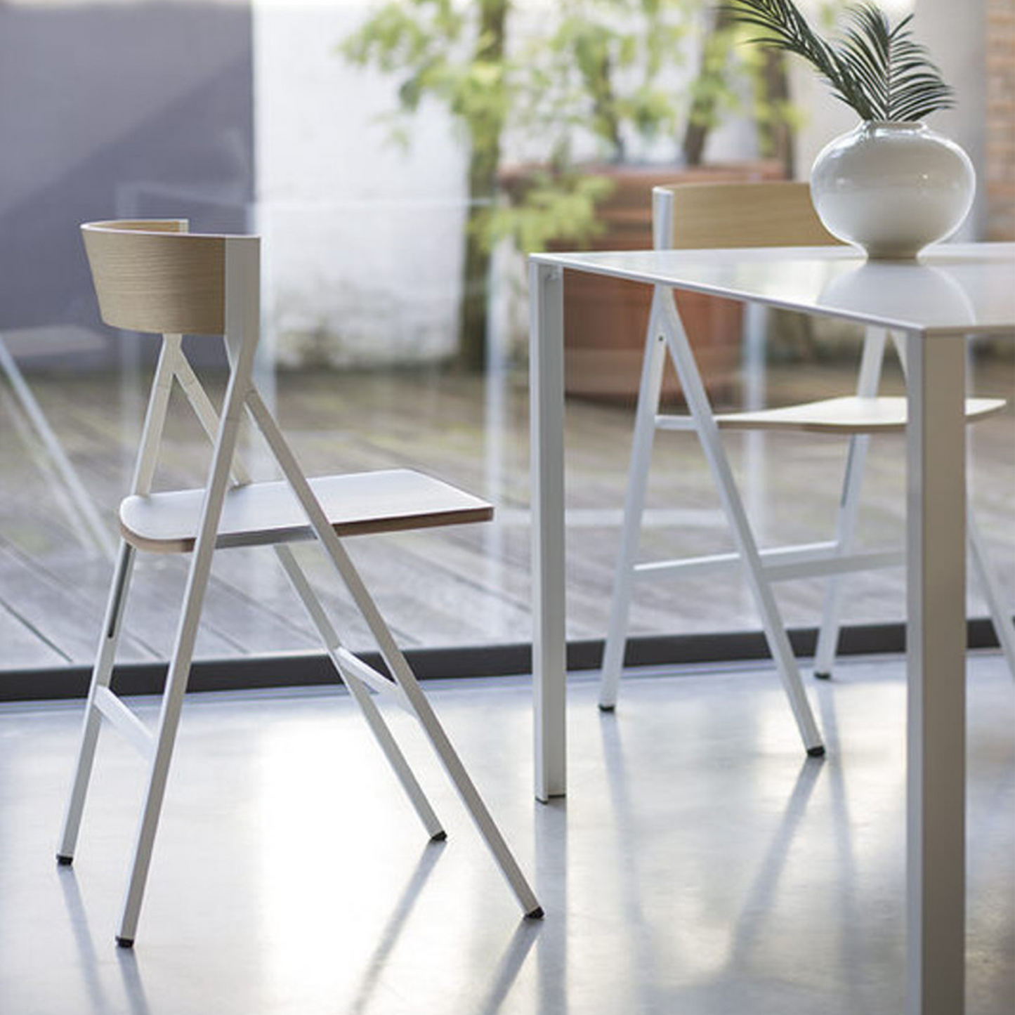 Folding chair with curved back set up at dining table.