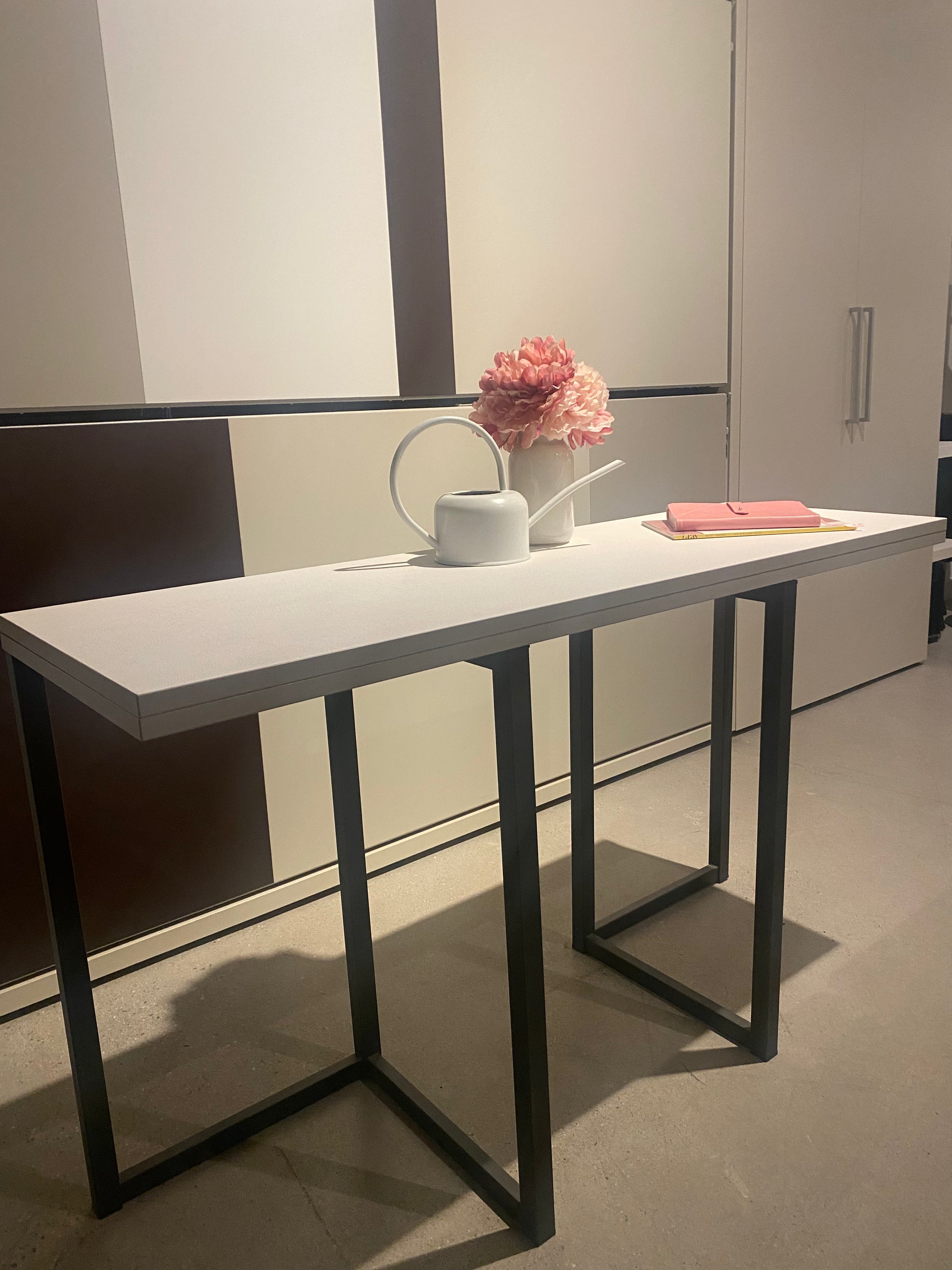 Slim console table with vase of flowers atop it