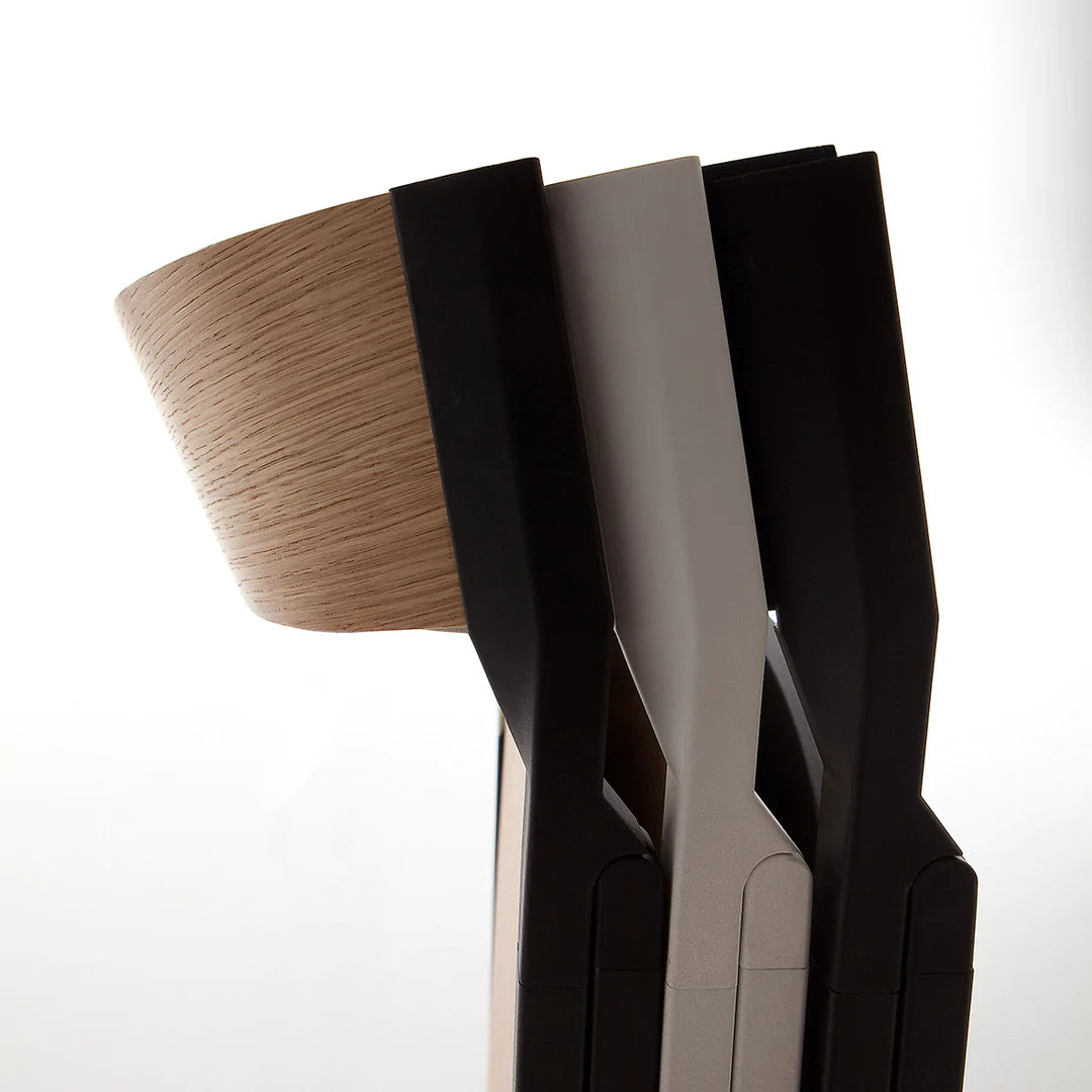 Close up of folding dining chairs with curved backrest stacked against each other.
