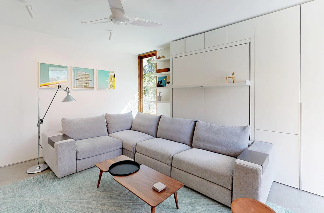 Closet with split doors next to wall bed with sectional sofa.