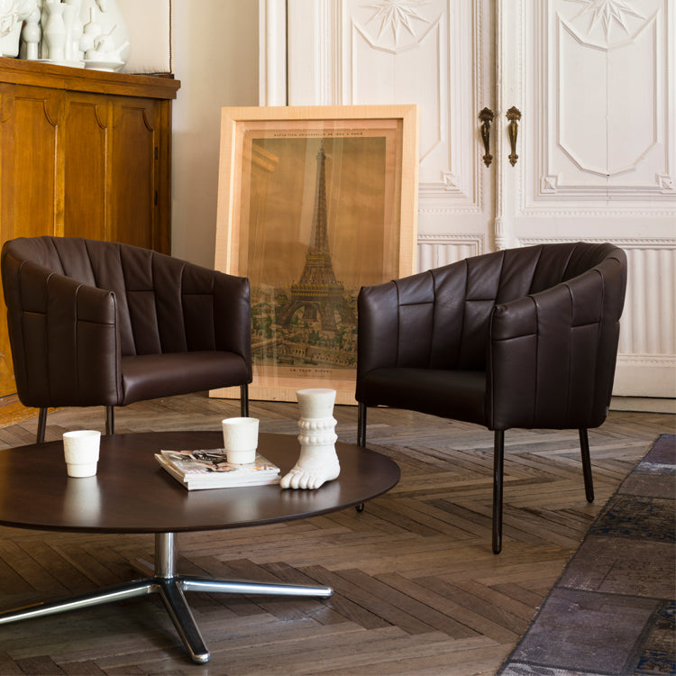 Brown leather armchair with ribboned seat and three legs.